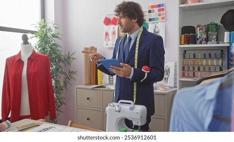 Handsome hispanic man using tablet in a tailor shop surrounded by fashion sketches and sewing items. - Powered by Shutterstock