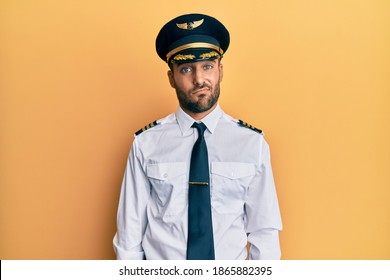 Handsome Hispanic Man Wearing Airplane Pilot Uniform Looking Sleepy And Tired, Exhausted For Fatigue And Hangover, Lazy Eyes In The Morning. 