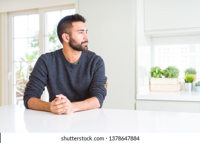 Handsome Hispanic Man Wearing Casual Sweater At Home Looking To Side, Relax Profile Pose With Natural Face With Confident Smile.