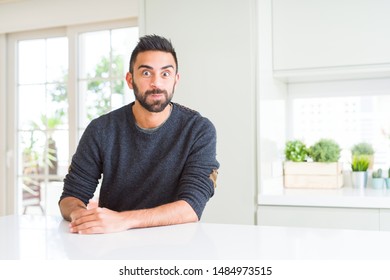 Handsome hispanic man wearing casual sweater at home puffing cheeks with funny face. Mouth inflated with air, crazy expression. - Shutterstock ID 1484973515