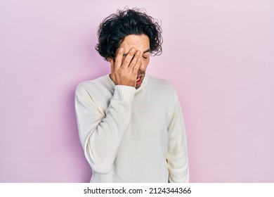 Handsome Hispanic Man Wearing Casual White Sweater Yawning Tired Covering Half Face, Eye And Mouth With Hand. Face Hurts In Pain. 