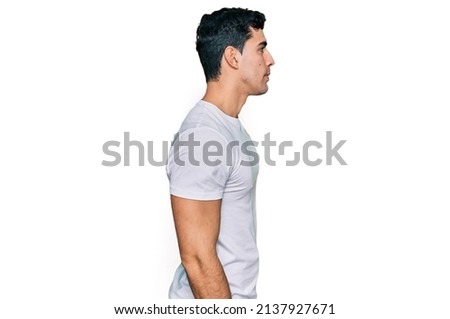 Handsome hispanic man wearing casual white t shirt looking to side, relax profile pose with natural face with confident smile. 