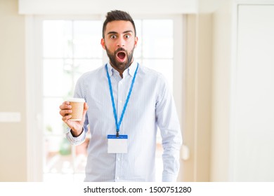 Handsome hispanic man wearing id card and drinking a cup of coffee scared in shock with a surprise face, afraid and excited with fear expression - Shutterstock ID 1500751280