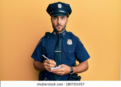 Handsome Hispanic Man Wearing Police Uniform Writing Traffic Fine Relaxed With Serious Expression On Face. Simple And Natural Looking At The Camera. 