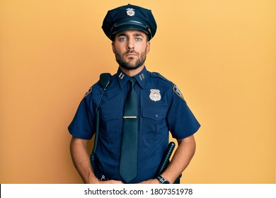 Handsome Hispanic Man Wearing Police Uniform Relaxed With Serious Expression On Face. Simple And Natural Looking At The Camera. 