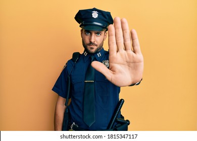 Handsome hispanic man wearing police uniform doing stop sing with palm of the hand. warning expression with negative and serious gesture on the face.  - Powered by Shutterstock