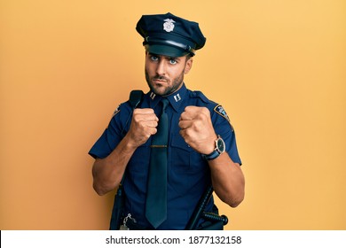 Handsome Hispanic Man Wearing Police Uniform Ready To Fight With Fist Defense Gesture, Angry And Upset Face, Afraid Of Problem 