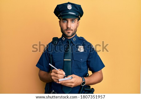 Handsome hispanic man wearing police uniform writing traffic fine relaxed with serious expression on face. simple and natural looking at the camera. 
