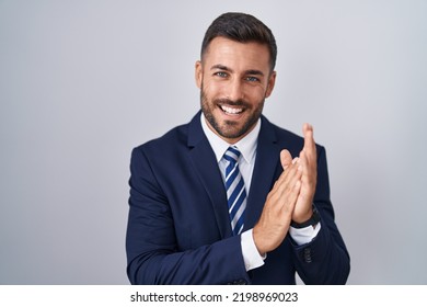 Handsome Hispanic Man Wearing Suit And Tie Clapping And Applauding Happy And Joyful, Smiling Proud Hands Together 