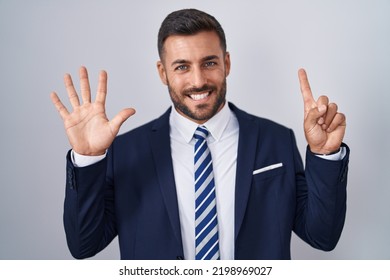 Handsome hispanic man wearing suit and tie showing and pointing up with fingers number six while smiling confident and happy. 