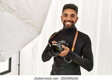 Handsome hispanic man working as professional photographer at photography studio. Standing holding camera smiling confident. - Powered by Shutterstock