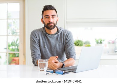 Handsome Hispanic Man Working Using Computer Laptop With Serious Expression On Face. Simple And Natural Looking At The Camera.