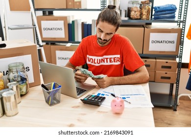 Handsome hispanic man working as volunteer calculating donations at donation stand - Shutterstock ID 2169843091