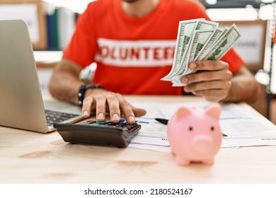 Handsome hispanic man working as volunteer calculating donations at donation stand - Shutterstock ID 2180524167