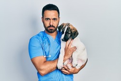 Handsome Hispanic Veterinary Man With Beard Checking Dog Health Skeptic And Nervous, Frowning Upset Because Of Problem. Negative Person. 