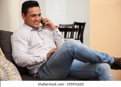 Handsome Hispanic Young Man Talking On His Cell Phone While Relaxing At Home