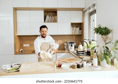 Handsome Husband Holding Adorable Lovely Son In Arms Throwing Up Kneading Homemade Pizza Baking Preparing Surprise For Family Dinner.