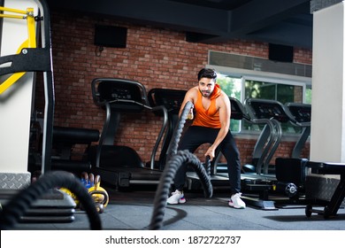 Handsome Indian Asian Young Man Doing Battle Rope Exercise While Working Out In Gym, Selective Focus