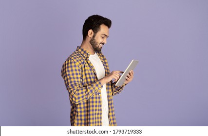 Handsome Indian Guy Using Tablet Computer For Online Work Or Communication On Violet Background, Panorama