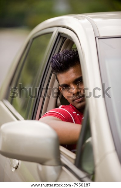 A handsome Indian man in a saloon car outside
in countryside