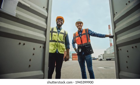 Handsome Industrial Engineer and African American Supervisor in Hard Hats and Safety Vests Opening a Shipping Cargo Container in Logistics Terminal. Both Colleagues Look Happy When Opening the Doors. - Powered by Shutterstock