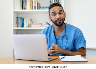 Handsome Latin American Male Nurse Talking With Patient At Computer At Hospital