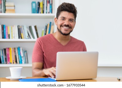 Handsome Latin American Man With Beard Working At Computer At Home