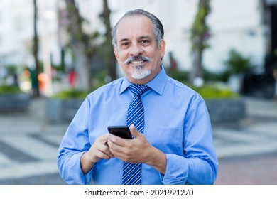 Handsome Latin American Senior Businessman Shopping Online With Phone Outdoor In City In Summer