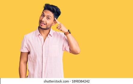 Handsome latin american young man wearing casual summer shirt smiling pointing to head with one finger, great idea or thought, good memory 
