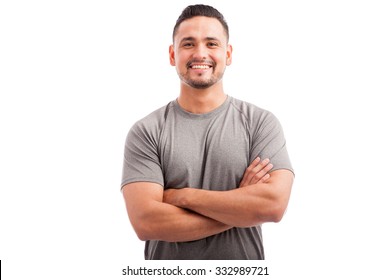 Handsome Latin athlete in a sporty outfit with his arms crossed and smiling on a white background