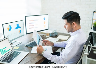 Handsome Latin Businessman Examining Sales Data While Working At Home