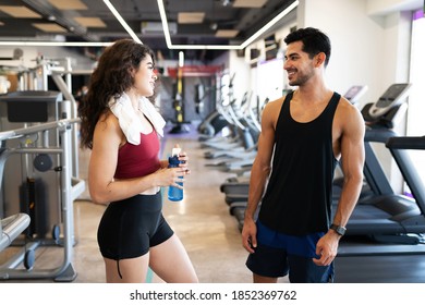 Handsome Latin Couple Talking, Flirting And Drinking Water Between Workouts At The Fitness Center