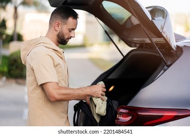 Handsome Latin Man Loading Bag In Car Trunk. Driver Planning Road Trip, Transportation Concept 