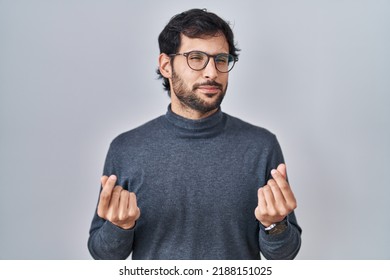 Handsome Latin Man Standing Over Isolated Background Doing Money Gesture With Hands, Asking For Salary Payment, Millionaire Business 