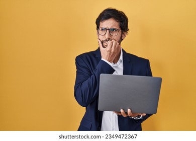 Handsome latin man working using computer laptop looking stressed and nervous with hands on mouth biting nails. anxiety problem. 