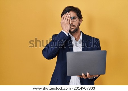 Handsome latin man working using computer laptop yawning tired covering half face, eye and mouth with hand. face hurts in pain. 