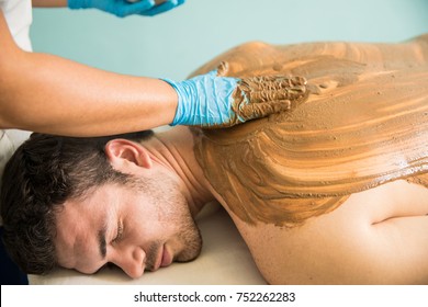 Handsome Latin Young Man Getting A Massage And A Mud Bath During His Visit At A Spa