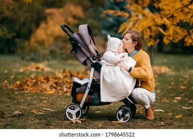 Handsome little baby with big blue eyes, short red hair, pump lips in a stroller outside in the fall with its nice happy mum