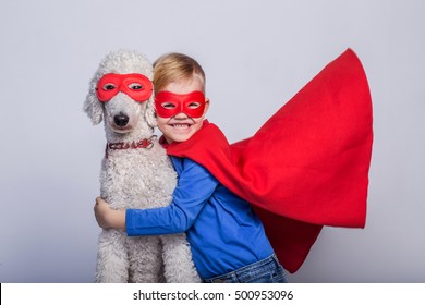 Handsome Little Superman With Dog. Superhero. Royal Poodle. Studio Portrait Over White Background