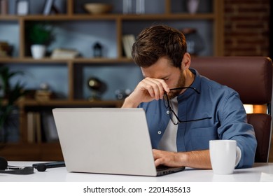 Handsome Male Businessman Manager Working Tiredly Behind A Laptop In A Stylish Home Office. Loss Of Vision From The Screen. Fatigue And Burnout From Work. Overwork And Stress.