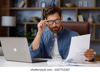 Handsome male businessman manager working behind a laptop in a stylish home office. Remote work at home. Portrait of a successful freelancer. - Shutterstock ID 2207715347