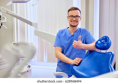 Handsome male dentist in a room with medical equipment on background. - Shutterstock ID 628968494