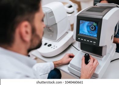 Handsome male doctor  ophthalmologist is checking the eye vision of attractive young woman in modern clinic. Doctor and patient in ophthalmology clinic.