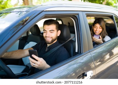 Handsome Male Driver And Female Passenger Smiling While Looking At The Ride Share App On The Smart Phone