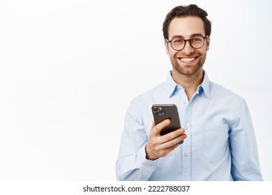 Handsome male entrepreneur using mobile phone, standing in glasses and blue shirt over white background. - Powered by Shutterstock