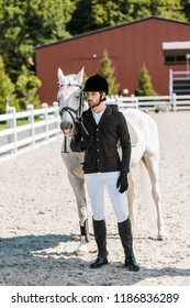 Handsome Male Equestrian Standing Near Horse And Looking Away At Horse Club