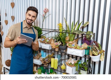 Handsome Male Florist Using Digital Tablet And Smiling At Camera While Working In Flower Shop