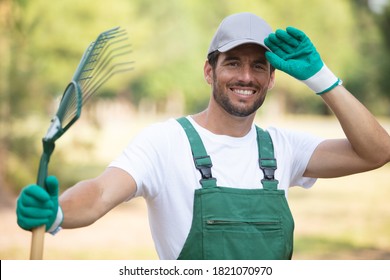 handsome male gardener holding a rake - Powered by Shutterstock