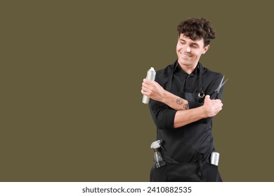 Handsome male hairdresser in black apron with scissors and hair spray on green background - Powered by Shutterstock