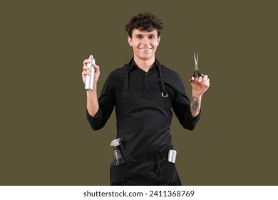 Handsome male hairdresser in black apron with scissors and hair spray on green background - Powered by Shutterstock